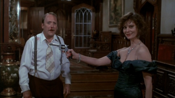 A shot from the film Clue, where Mrs. White holds a gun in front of Col. Mustard